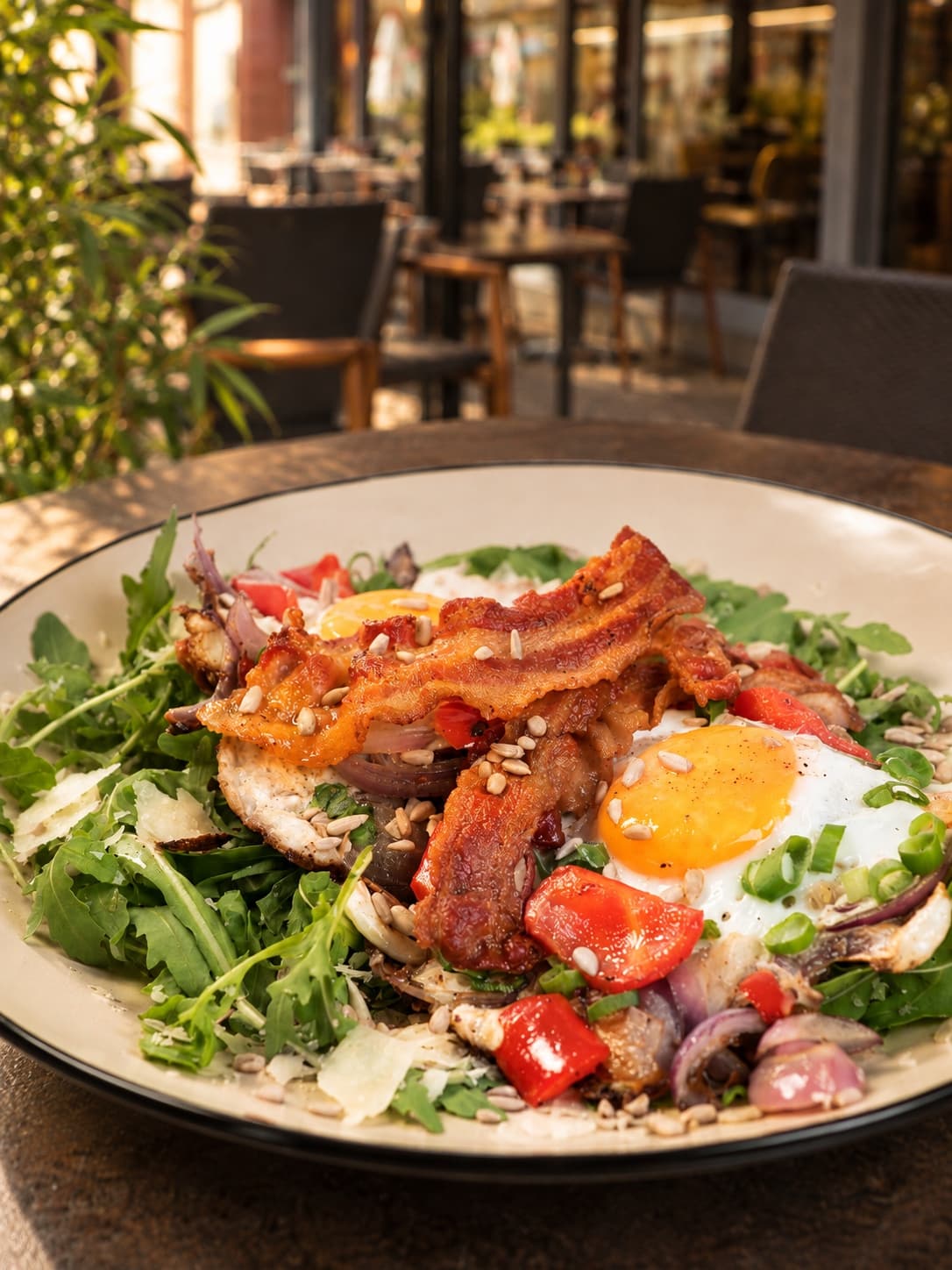 Herzhaftes Frühstück mit Ei, Speck und Salat auf einer Terrasse
